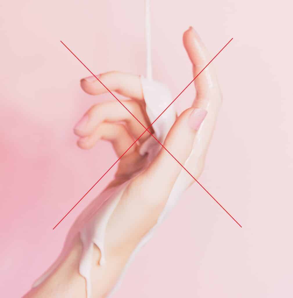 Photo d'une main avec un liquide pour illustrer le fait de ne pas hydrater ses mains avant une pose d'ongles